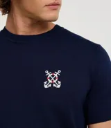 Remera azul marino de viscosa con cuello redondo y mangas cortas. Presenta un bordado con motivos marineros en el frente. Corte regular.
