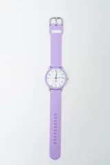 Reloj analógico con caja redonda y correa de silicona color lila. La esfera es blanca con números e indicadores en negro. Posee hebilla metálica plateada.