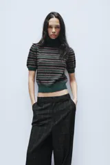 Jersey de punto con cuello subido y manga corta, diseño a rayas horizontales en tonos verde oscuro, negro y rosado.