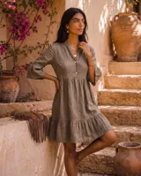 Vestido corto verde militar de lino 100%, con cuello mao, escote con dos botones y mangas tres cuartos con volados. Presenta corte en la cintura y falda con vuelo terminada en volado en el ruedo.