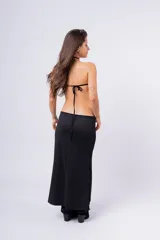 Vestido largo negro con escote halter, aberturas laterales y detalle de aros metálicos.