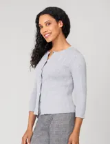 Cardigan blanco de tejido liviano con trama en relieve, cuello a la base y cierre frontal con botones a tono. Presenta mangas tres cuartos.