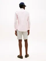 Camisa de popelina rosa claro con tecnología flex, corte slim, cuello abotonado, cierre con botones, logo de Tommy Hilfiger bordado en el pecho y detalles distintivos de la marca.