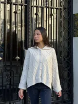 Saco tejido de punto con diseño de ochos y trenzas, color negro. Presenta cuello estilo camisero, cierre frontal con botones tipo joya, mangas holgadas y silueta oversize.