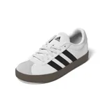 Zapatillas Adidas VL Court 3.0, de cuero blanco con las tres tiras clásicas en negro, detalles en gamuza gris en la puntera y el talón, y suela marrón.
