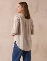 Blusa color beige de lino, marca Dash. Cuello a la base, escote en V y abertura con botones. Delantera con bolsillos. Largo de manga regulable con presilla y botón.