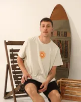 Remera unisex color crema con estampado de un sol anaranjado.