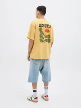 Remera color crema con estampado de flor y texto 'Super Natural' en la espalda.