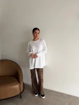 Pantalón tipo oxford de tiro alto con estampado animal print de leopardo, corte ajustado en la parte superior y acampanado desde la rodilla hacia abajo.