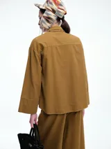 Camisa oversize de lyocell color tostado, con cuello clásico, cierre frontal de botones y mangas largas con puños anchos. Presenta un diseño de corte relajado con caída fluida.