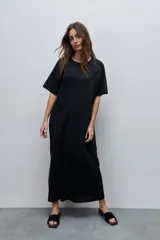 Vestido largo negro de corte recto y holgado, con mangas cortas amplias y cuello redondo.