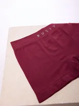 Boxer de diseño sin costuras en color bordó, con cintura elástica ancha que presenta el nombre de la marca Rusty estampado en tono contrastante.