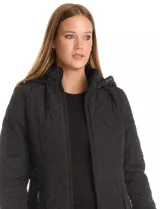 Campera capitoneada de largo midi en color bordó, con diseño de rombos en el cuerpo y mangas, y costuras diagonales en los laterales. Cuenta con cierre frontal, capucha desmontable con interior suave y panel entallado en la cintura.