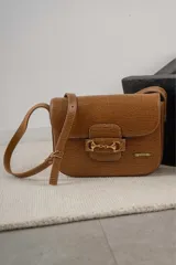 Cartera de cuero color tostado con textura de piel de lagarto, solapa frontal y cierre metálico dorado con diseño de estribo. Incluye correa ajustable y placa con el logo de la marca "LELE".