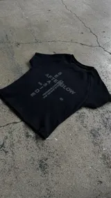 Remera negra ajustada de manga corta con estampado gráfico frontal en tonos grises que incluye la inscripción "Afterglow" y motivos tipográficos.