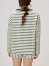Remera manga larga de corte oversize y cuello redondo, con diseño a rayas horizontales en tonos claros y verde militar, y detalle de bordado frontal.