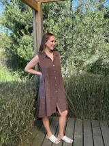 Vestido camisero marrón de lino italiano, sin mangas, con cuello camisero y cierre frontal con botones de nácar. Corte a la rodilla con abertura frontal.