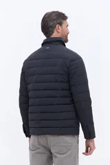 Campera puffer negra de líneas horizontales, con cuello camisero y cierre frontal oculto. Presenta un diseño minimalista con bolsillos laterales funcionales.