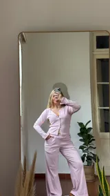 Remera de manga larga en tejido rib, color rosa, con escote en V y cierre frontal con botones a presión metálicos.
