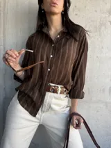 Camisa marrón a rayas verticales blancas, de corte holgado y manga larga.