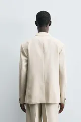 Blazer de corte regular fit confeccionado en tejido con lana. Presenta cuello con solapas de muesca, cierre frontal de un botón, bolsillos de vivo en el pecho y en la cadera, y aberturas en la espalda.