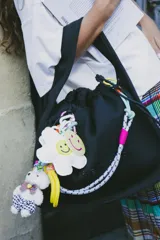 Bolso negro tipo tote bag con textura acanalada, cierre con cordón ajustable, tres bolsillos internos y logo en relieve.