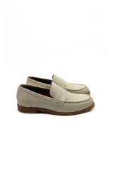 Mocasín tipo penny loafer de cuero negro charol, con costura visible en la puntera y tira de adorno sobre el empeine. Suela baja y gruesa.