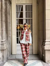 Pantalón de corte recto con estampado de cuadros en tonos rojos, marrones y beige. Presenta un diseño de tiro medio y pernera amplia.