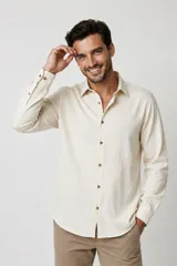 Camisa de viscosa color beige con sutiles rayas verticales, cuello camisero, manga larga y botones frontales en contraste.