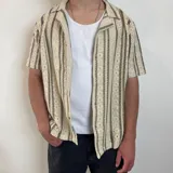 Camisa de crochet color crema con rayas verticales marrones, cuello clásico y corte boxy.