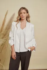 Chaqueta de satén color blanco, con diseño abierto sin botones, cuello mao y mangas largas con puños rectos.
