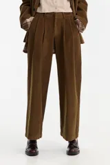 Pantalón ancho de pana color marrón, con tiro bajo, pinzas delanteras y largo hasta el tobillo.