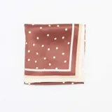 Pañuelo cuadrado de raso color marrón con estampado de lunares blancos y borde en tono crema.