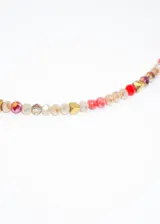 Gargantilla corta de acero quirúrgico hipoalergénico con mostacillas brillantes de colores y dije central dorado en forma de rombo.