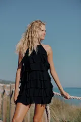 Vestido mini negro de cuello halter y espalda descubierta, con diseño de múltiples volantes en cascada.