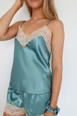 Pijama de satén elastizado color champagne, compuesto por musculosa con escote en V y detalle de puntilla elastizada, y short con elástico en la cintura y terminación con puntilla.