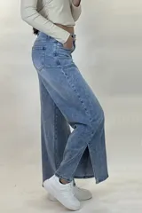 Pantalón de jean estilo wide leg con tiro alto, costuras verticales decorativas en el frente y corte diagonal en la parte inferior de las piernas.