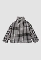 Campera corta de corte boxy con cuello alto y cierre frontal mediante botones metálicos a presión. Presenta un diseño de estampado escocés en tonos grises, negros y líneas finas rosadas.