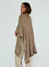 Ruana de tejido de punto color marrón, con diseño abierto y borde de encaje en el dobladillo.