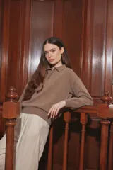 Sweater de punto color taupe, con cuello polo y cierre frontal parcial de botones, de manga larga y calce holgado.