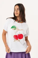 Remera blanca de algodón y elastano, con cuello redondo y mangas cortas. Estampado frontal con cerezas y texto en dorado.