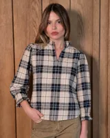 Blusa de algodón con estampa a cuadros en tonos beige, negro y blanco. Cuenta con cuello mao con volados, escote en V y mangas largas con puños fruncidos elastizados.