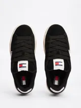 Zapatillas Tommy Jeans de corte bajo, color negro, con exterior de ante, interior de poliéster y suela de goma color caramelo. Presentan un panel a contraste en el talón, logo de Tommy Jeans en la lengüeta y etiqueta de la marca en el lateral.
