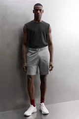 Pantalones cortos de algodón color gris, con cintura elástica ajustable con cordón y parche con logo. Incluye bolsillos laterales y un bolsillo trasero. Presenta bandas laterales a tono, bordado y estampado combinado a contraste en el delantero y la espalda, y aberturas laterales en el bajo.