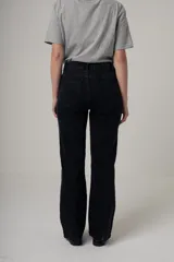 Jean de denim negro, tiro alto y corte recto, con costuras verticales decorativas en el frente.