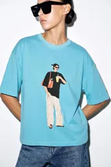 Camiseta oversize de algodón con efecto lavado, color celeste, cuello redondo, manga corta y estampa frontal de la artista Philippa Coules.
