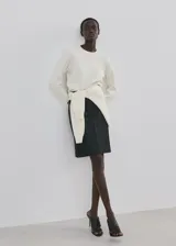 Sweater de punto color blanco crudo, con cuello redondo y mangas largas.