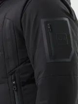 Campera híbrida Boss modelo OW_Block-X, color negro, con cuerpo acolchado y mangas de tejido liso. Presenta capucha fija, cierre frontal completo y bolsillos laterales con cierre.