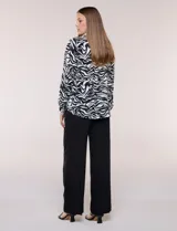 Camisa de gasa Ninety Clothing con estampado animal print en blanco y negro, cuello con solapa, escote en V, cierre frontal con botones y manga larga.