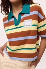 Remera tejida de algodón con cuello polo amarillo, corte boxy y estampado de rayas horizontales en tonos azul claro, marrón, rojo y amarillo.